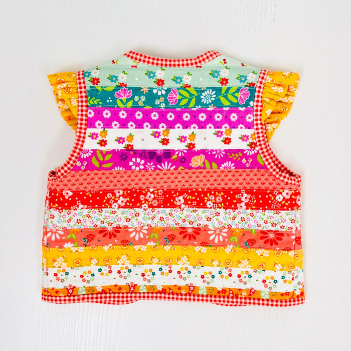 A colorful sleeveless baby vest with ruffle sleeves, featuring a vibrant horizontal striped patchwork design of floral and patterned fabric panels, set against a plain white background.